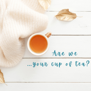 A white cup of tea, on a white wooden floor with blue text asking 'are we your cup of tea?'